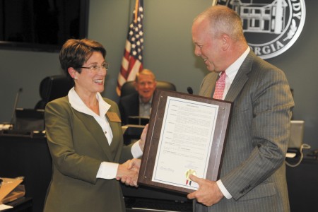 Caption: City Councilwoman Adrian Bonser, left, receives a resolution from Mayor Mike Davis.