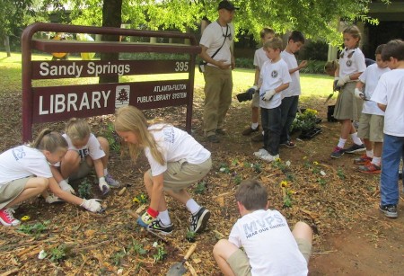 Mount Vernon Presbyterian third-graders help plant flowers in front of the Sandy Springs Library sign.