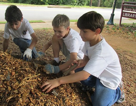 From left, Mount Vernon third-graders Curran Jolly, Zack Betz and Brooks Scarborough lay down mulch at the Sandy Springs Library.