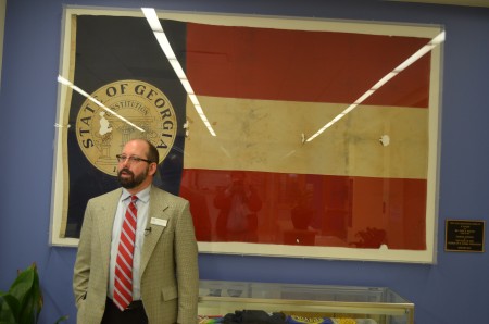 E. Rivers Principal Matthew Rogers stands in front of a Georgia state flag that was “rescued” by 11-year-old John Maltby when the school burned to the ground in 1948.