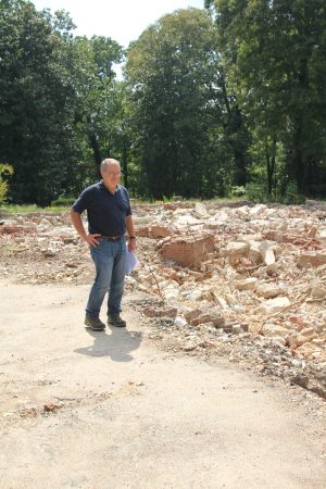 Mike Rabalais, who long maintained the former Glenridge Hall estate, stands next to the demolished mansion's ruins during an August 2015 site tour. (Photo John Ruch)