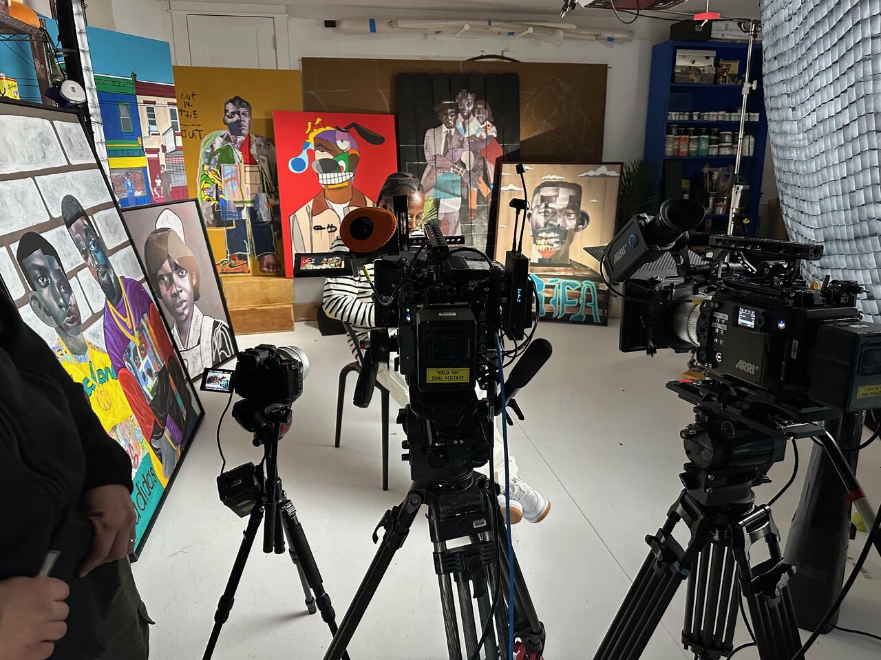 Filmhold med ARRI-kameraer klar til et interview inde i et kunststudio omgivet af store moderne malerier.