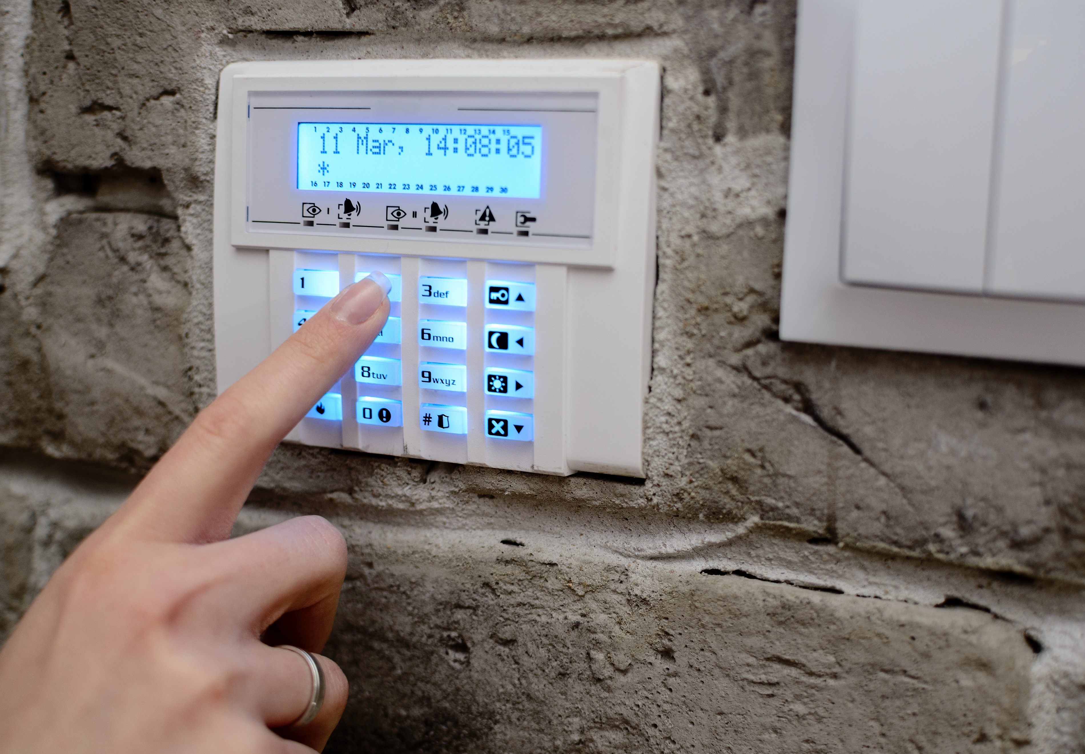 a hand pushing security alarm buttons
