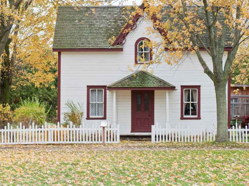 white and red wooden house with fence